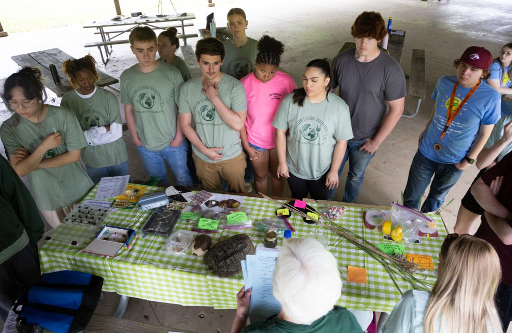 Students gathered around table, with aquatic teaching tools.