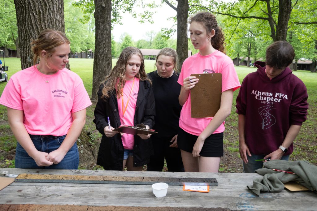 Young ladies in pink team shirts looking at soil.