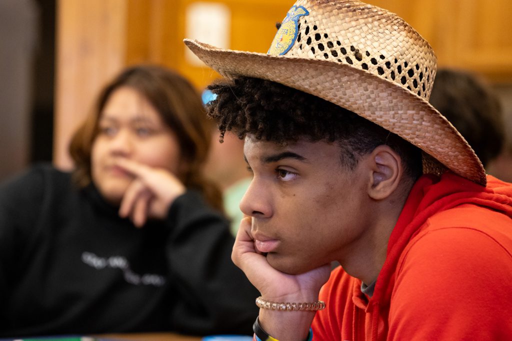 Young man in hat listens to presentation.